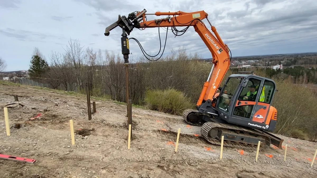 Grävmaskin installerar skruvpålar på brant sluttning för Jätemäki träningstrappor, Helsingfors
